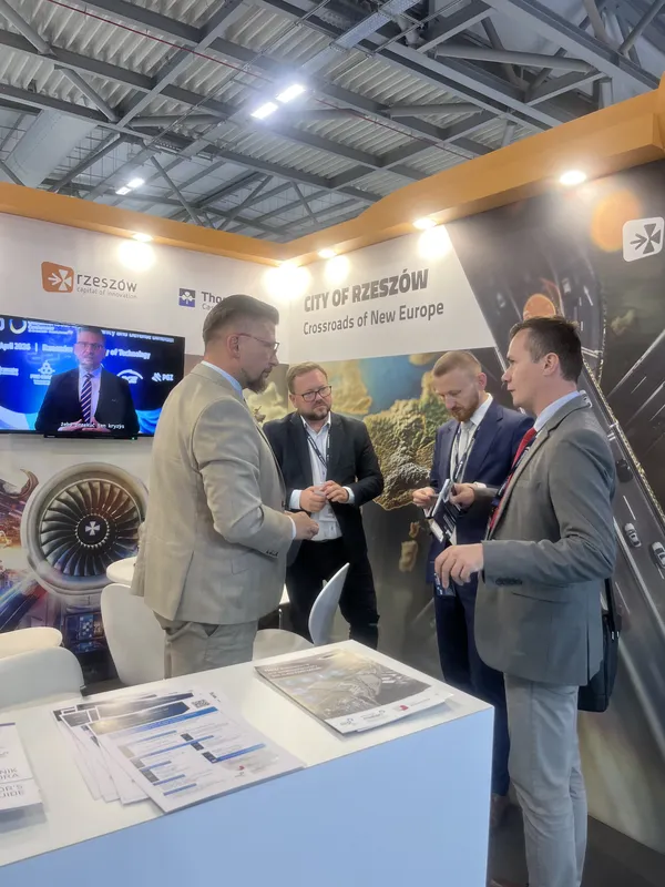 Cztery osoby prowadzą rozmowę biznesową przy stoisku promującym Rzeszów i region Podkarpacia podczas Farnborough International Airshow 2026.