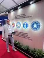 Uczestnik targów stoi przy stoisku prezentującym programy współpracy międzynarodowej amerykańskiego sektora obronnego podczas Farnborough International Airshow 2026.