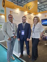 Trzy osoby stoją przy stoisku promującym Rzeszów i Podkarpacie podczas Farnborough International Airshow 2026, na tle materiałów dotyczących przemysłu lotniczego i inwestycji.