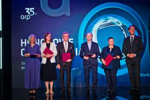 Siedem osób stoi na scenie podczas uroczystości, trzymając czerwone teczki z odznaczeniami. W tle widoczny jest napis „35 lat arp” oraz grafika sceniczna podświetlona niebieskim światłem.