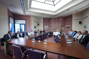 Uczestnicy spotkania biznesowego siedzący wokół długiego stołu w sali konferencyjnej z oknem dachowym.