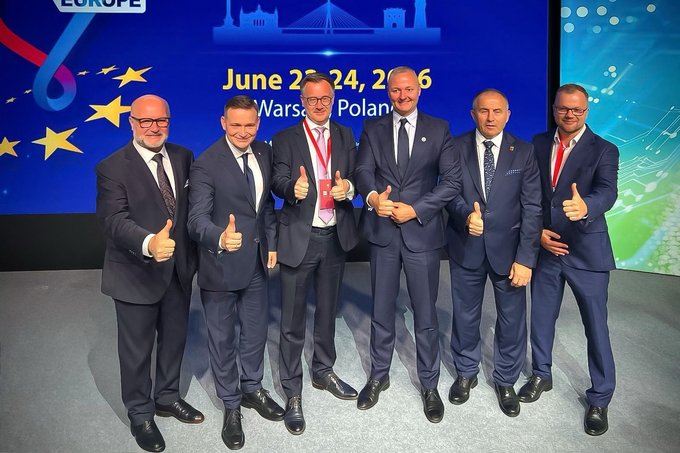 Przedstawiciele polskich instytucji i biznesu pozują wspólnie na scenie podczas Taiwan Expo in Europe 2026 w Warszawie na tle ekranu z datą i nazwą wydarzenia. Wszyscy mają na sobie garnitury, stoją w jednym rzędzie i pokazują kciuki uniesione w górę.